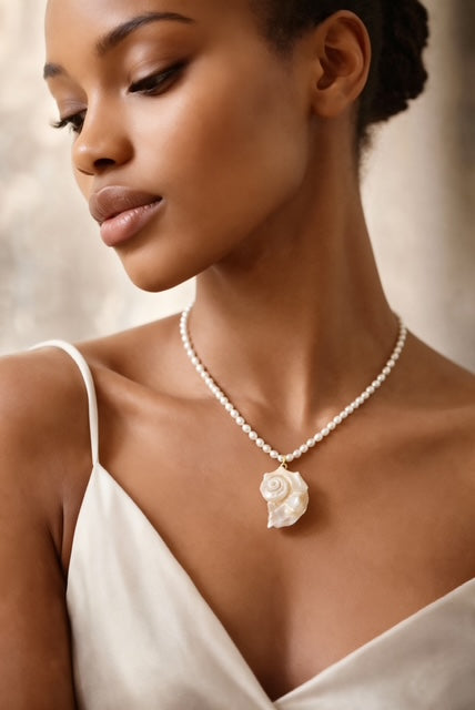 Ocean Whisper is a delicate, ocean-inspired necklace that captures the quiet magic of the sea. Strung with luminous freshwater mini rice pearls. At its center rests a graceful conch shell pendant, evoking the soothing rhythm of the tide and the timeless beauty of coastal shores.