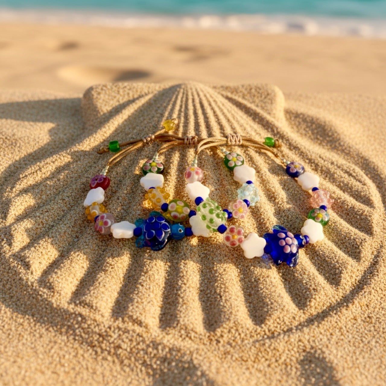 Colorful beaded bracelets on a sand dune with ocean in the background