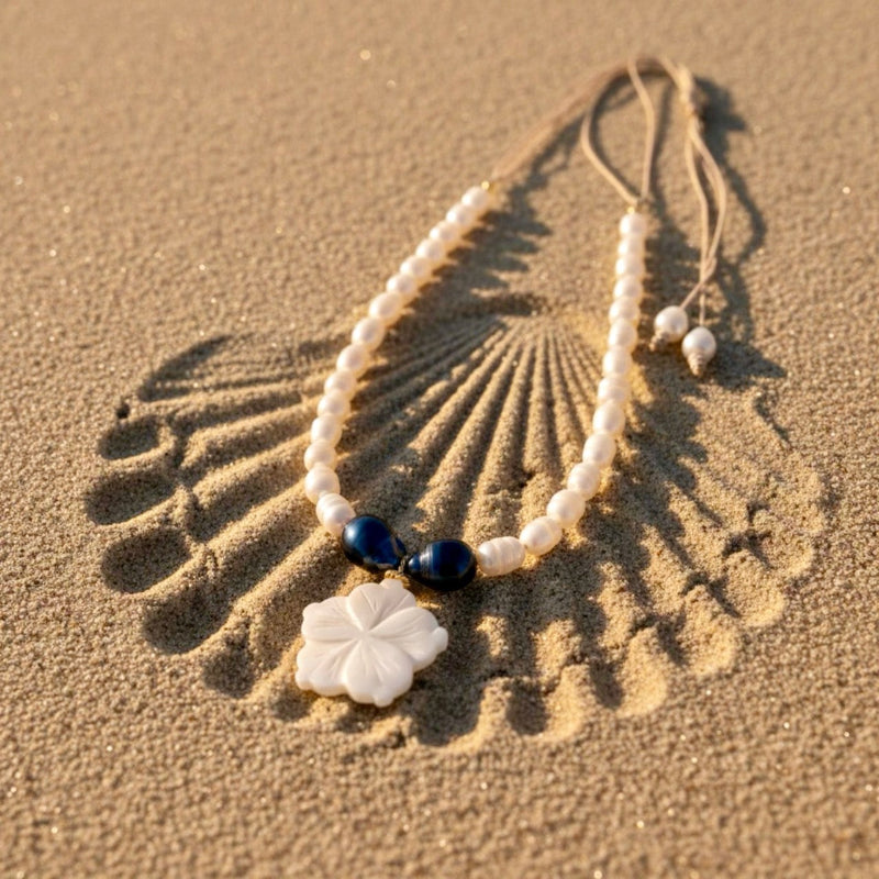 Isla Pearls: limited quantities nylon adjustable necklace with freshwater pearls and two baroque midnight-blue pearls surrounding a small nacre hibiscus pendant.