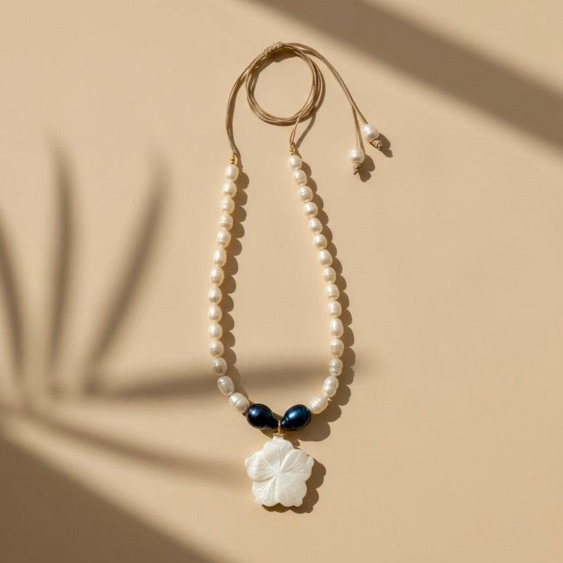Isla Pearls: limited quantities nylon adjustable necklace with freshwater pearls and two baroque midnight-blue pearls surrounding a small nacre hibiscus pendant.