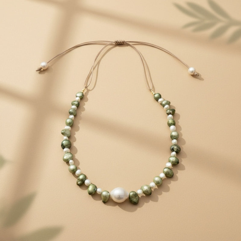 Isla Pearls: Limited quantities nylon adjustable necklace with green baroque pearls and freshwater pearls surrounding a white baroque pearl.