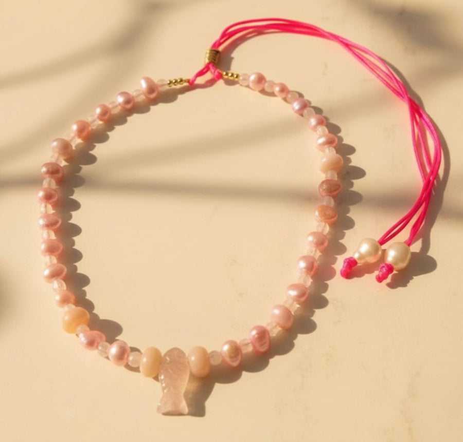 Inspired by the gentle beauty of the sea, the Pink Marina adjustable necklace captures the delicate beauty of ocean treasures in soft blush tones. Light pink freshwater pearls are paired with luminous rose quartz and gentle pink gemstones. At its heart rests a charming pink fish-quartz pendant, a symbol of serenity and freedom.