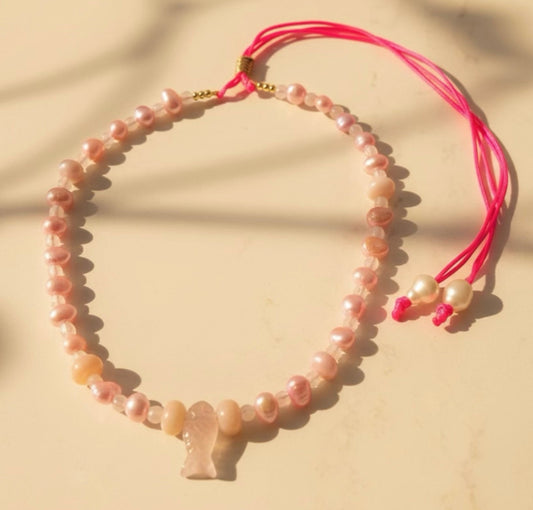 Inspired by the gentle beauty of the sea, the Pink Marina adjustable necklace captures the delicate beauty of ocean treasures in soft blush tones. Light pink freshwater pearls are paired with luminous rose quartz and gentle pink gemstones. At its heart rests a charming pink fish-quartz pendant, a symbol of serenity and freedom.