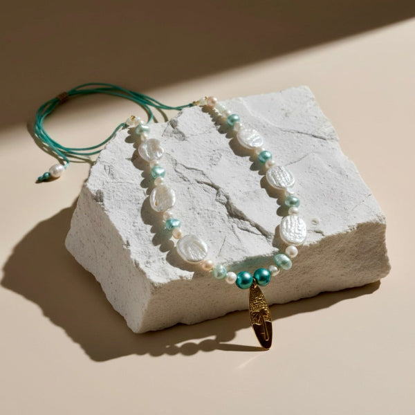 A dance of baroque coin pearls and turquoise and aqua freshwater pearls, crowned with a palm-embossed surfboard stainless steel pendant.