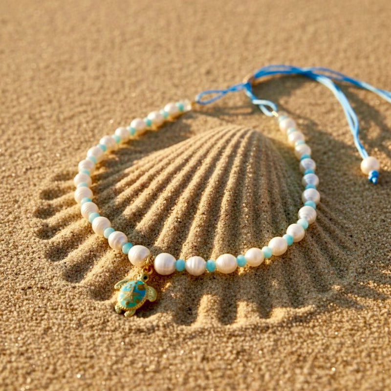 Embrace the serene beauty of the sea with the Cerulean Voyager adjustable necklace, combining light blue shell rondelles with lustrous freshwater pearls, finished with a charming stainless steel tortoise pendant.