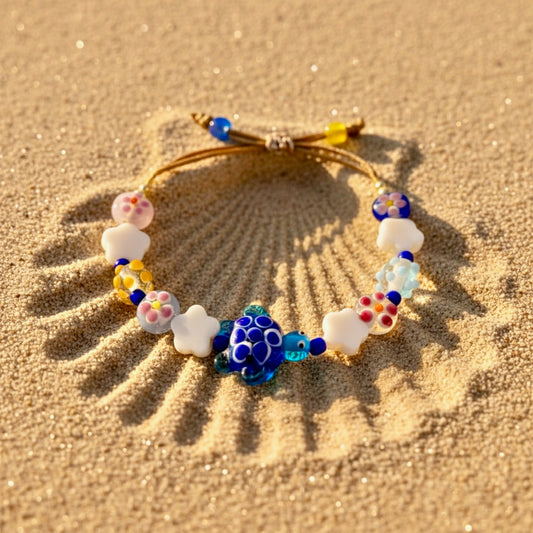 Colorful beaded bracelet with turtle charm on sand