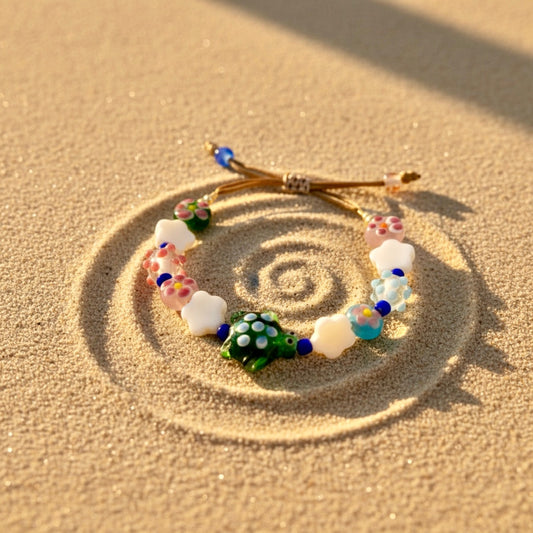 Colorful beaded bracelet on sand with a decorative bow