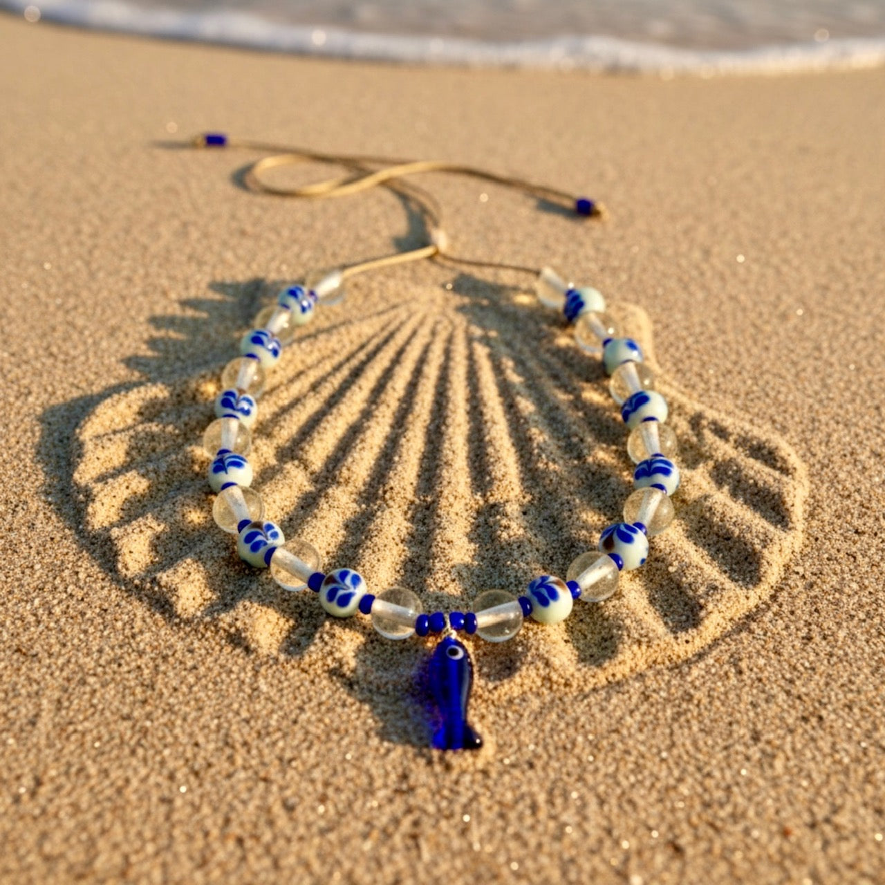 Beaded necklace with blue and white accents on a sand dune