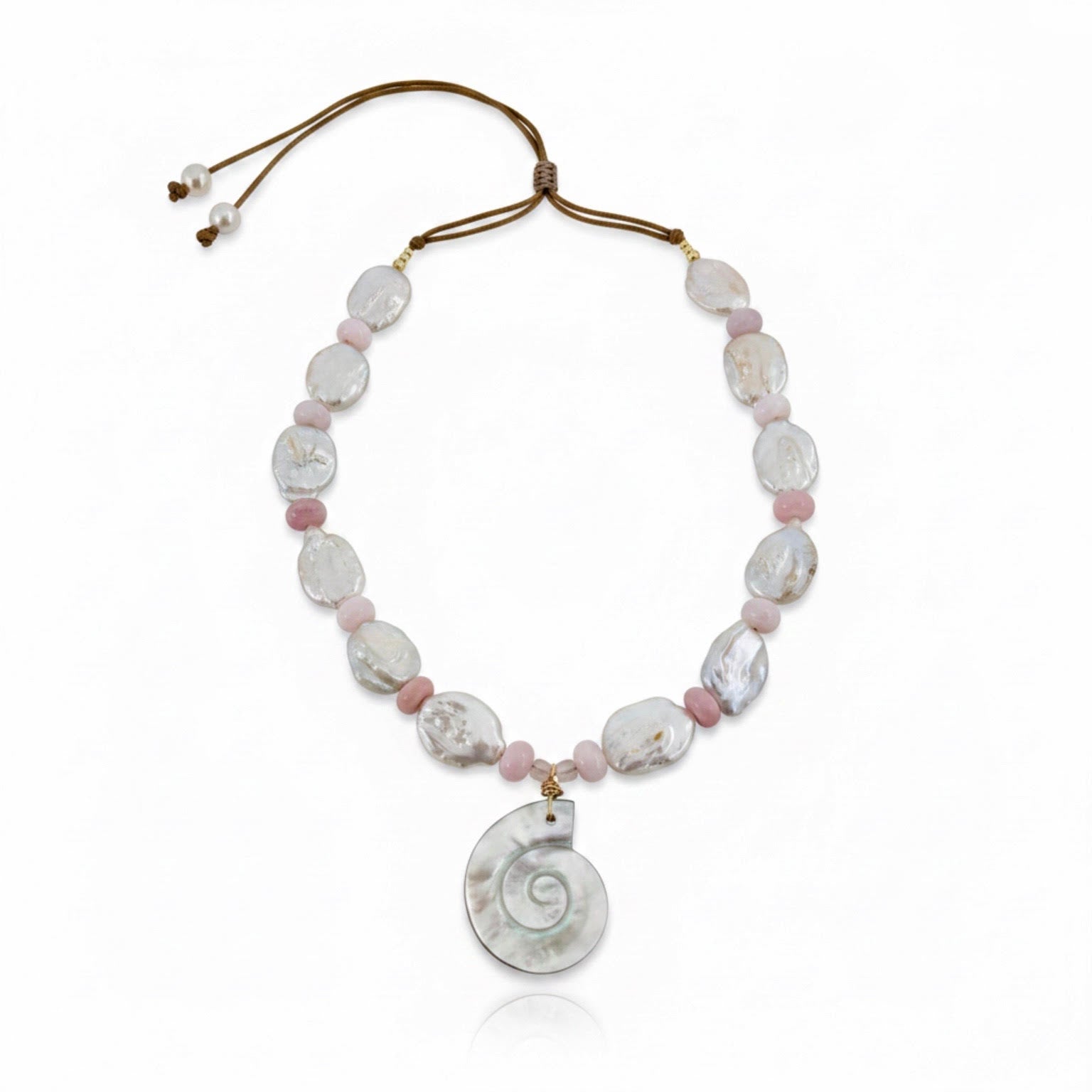 Ocean Muse – Blush is a delicate tribute to the quiet poetry of the sea at sunrise. This ethereal necklace features luminous baroque pearls, each uniquely shaped to celebrate nature’s organic beauty, paired with soft blush opal rondelles that glow with gentle, rosy iridescence. At its heart rests a carved conch pendant in radiant mother-of-pearl, evoking the whispers of ocean tides and treasured coastal memories.