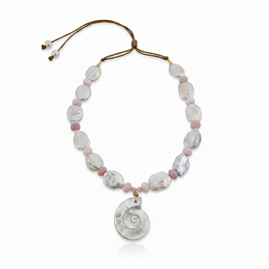 Ocean Muse – Blush is a delicate tribute to the quiet poetry of the sea at sunrise. This ethereal necklace features luminous baroque pearls, each uniquely shaped to celebrate nature’s organic beauty, paired with soft blush opal rondelles that glow with gentle, rosy iridescence. At its heart rests a carved conch pendant in radiant mother-of-pearl, evoking the whispers of ocean tides and treasured coastal memories.